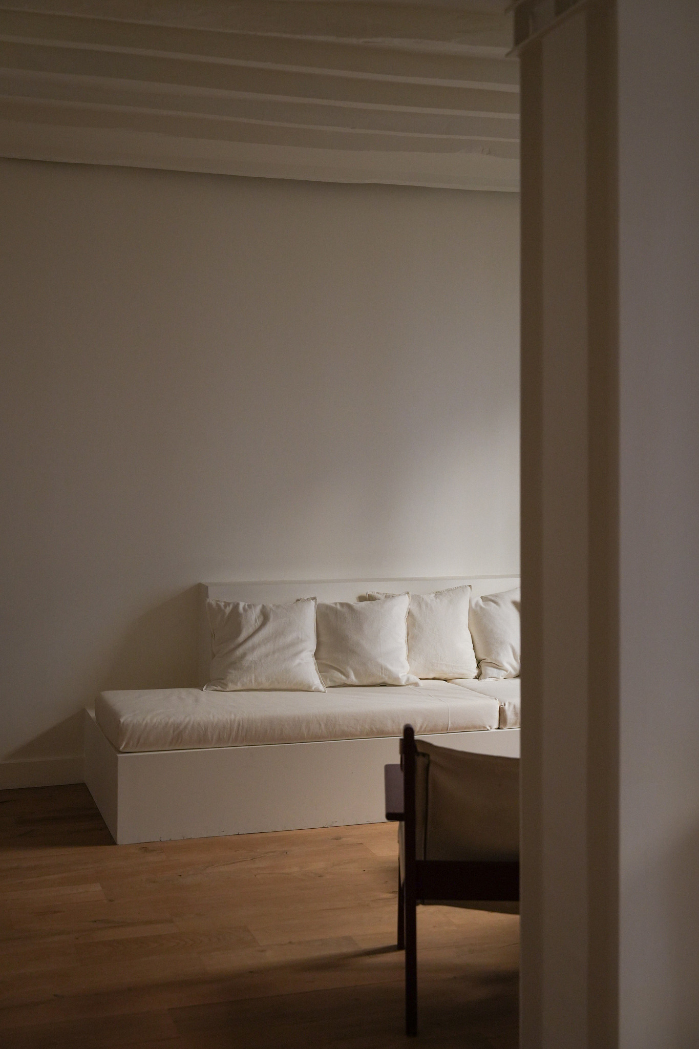 Banquette blanche cadrée depuis la pièce voisine