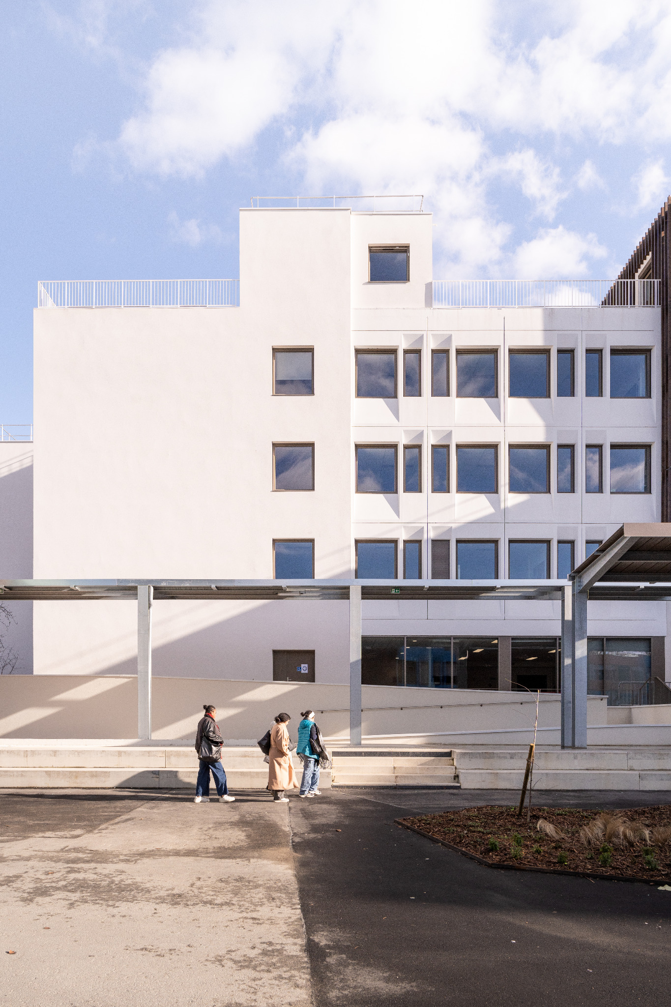 Façade blanche du groupe scolaire avec silhouettes